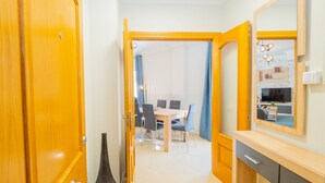 A hallway leading to a dining area with a table and chairs, a large mirror, and a vase.