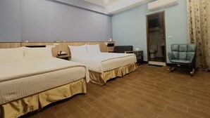 Une chambre d’hôtel avec deux lits, un bureau, une chaise, un appareil de climatisation et une porte donnant sur une salle de bain.