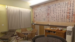 Une pièce avec une grande fresque murale, un coin repas comprenant une table et des chaises, un canapé et un petit réfrigérateur.