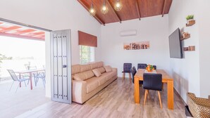 A modern living space with a wooden ceiling, a sofa, a dining table with chairs, and a TV mounted on the wall. - Cubo's Casa Rural Marifran / Private pool / Air conditioning (Alhaurín el Grande)