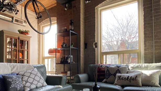 A modern living room with a glass coffee table, leather sofas, and a large window providing natural light. - 1+1 heritage loft in trendy dt Toronto (Toronto)