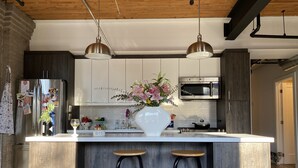 A modern kitchen with a central island, bar stools, stainless steel appliances, and pendant lighting. - 1+1 heritage loft in trendy dt Toronto (Toronto)