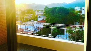 Un balcón con vistas a un paisaje urbano, incluyendo edificios y montañas.