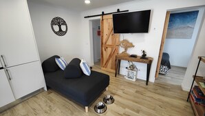 A modern living room with a sofa, a TV mounted on the wall, a wooden desk, and a sliding door.