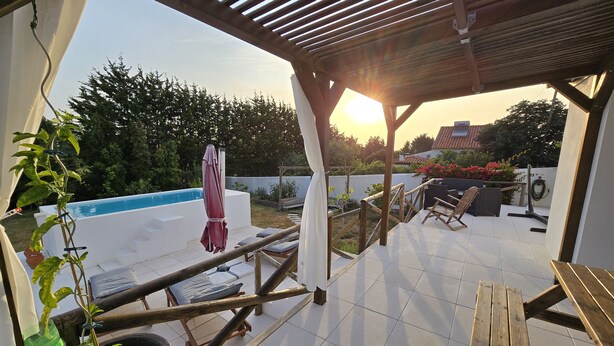 A covered patio area with a pool, outdoor furniture, and a pergola.