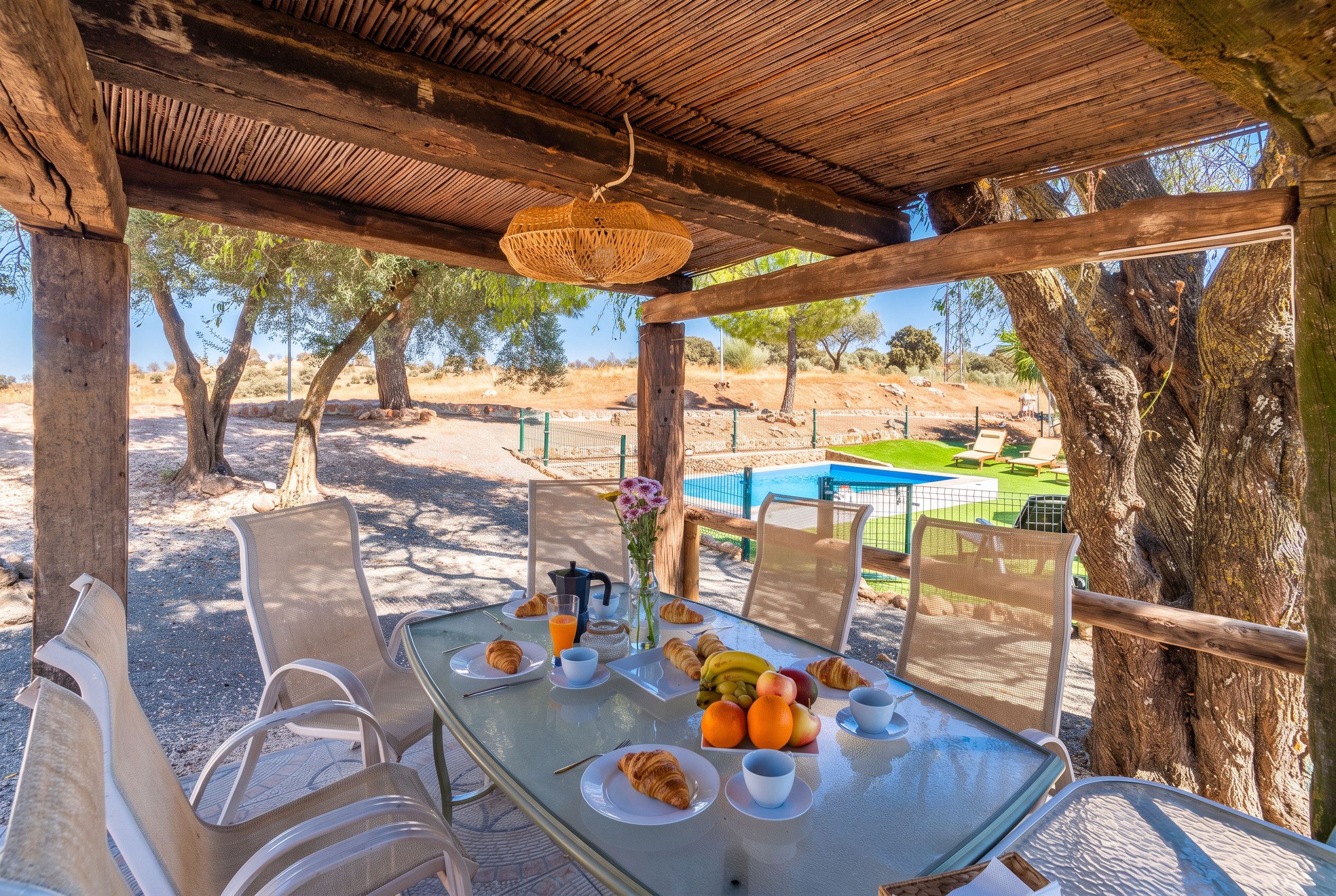 An outdoor dining area with a table set for breakfast, overlooking a pool and a desert landscape.