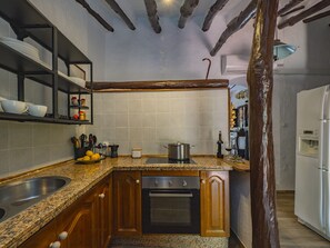 A compact kitchen with granite countertops, wooden cabinets, a built-in oven, and a stainless steel sink. - Cubo's Cortijo El Perezon / rural / private pool / air conditioning (Archidona)