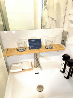 A bathroom with a wooden shelf holding two glasses, a sign, and toiletries. - Hotel Faranda Alisas Santander, Ascend Hotel Collection (Santander)