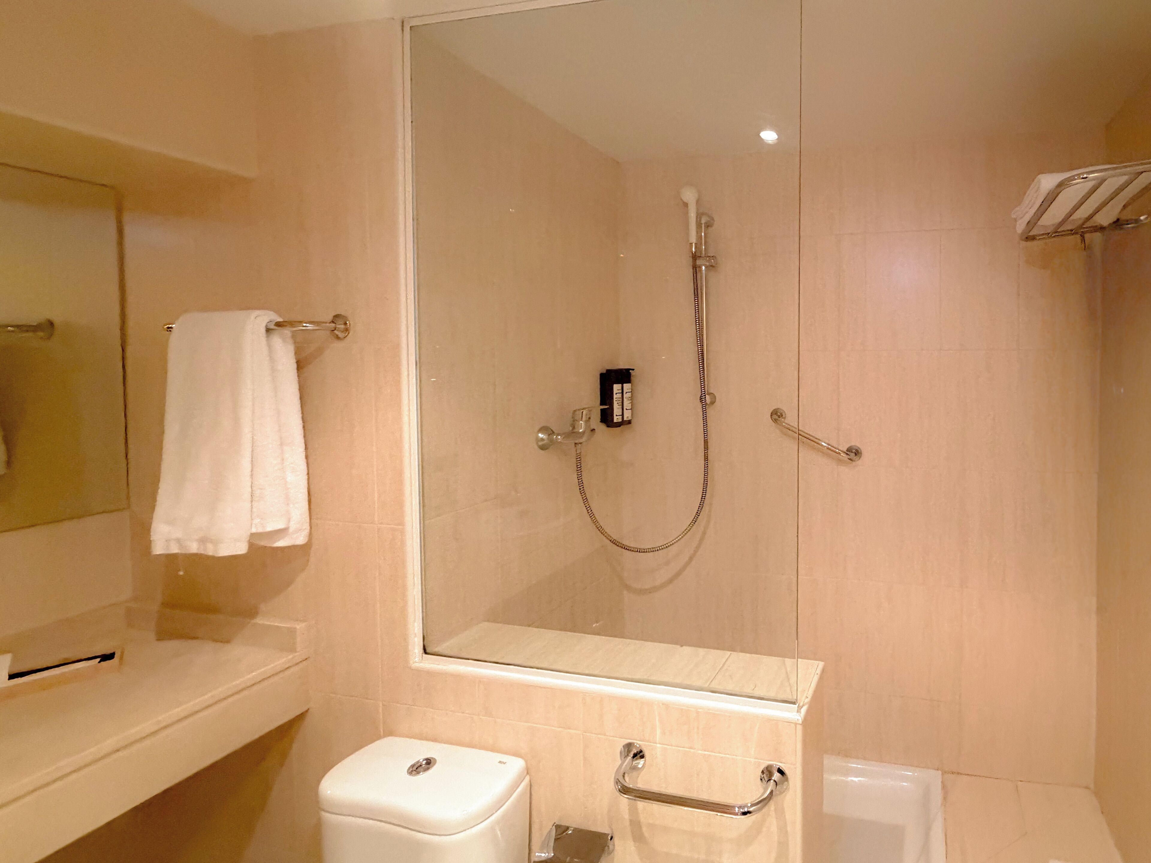 A modern bathroom with a glass-enclosed shower, a white sink, a mirror, and a towel rack.