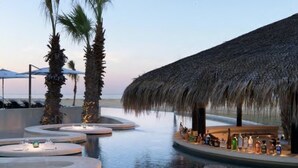 A pool area with circular seating and a bar area with umbrellas. - LUXURY STUDIO 5 🎖️, A PARADISIAC PLACE, IN FRONT OF THE SEA  (Cabo San Lucas)