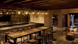 A bar area with a long wooden table, stools, and hanging light fixtures. - LUXURY STUDIO 5 🎖️, A PARADISIAC PLACE, IN FRONT OF THE SEA  (Cabo San Lucas)