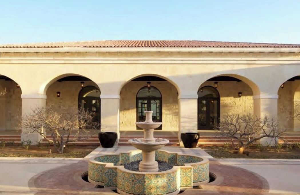 Une cour avec une fontaine, des arcades et la façade d’un bâtiment.