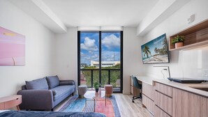 A modern apartment with a balcony, a sofa, a bed, a desk, and a TV. - Pastel Apartments (Miami)