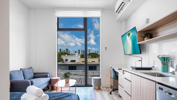 A modern apartment with a balcony, a sofa, a dining table, and a kitchen area. - Pastel Apartments (Miami)