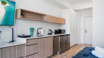 A modern kitchen with wooden cabinets, a built-in microwave, and a coffee maker.