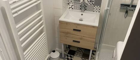 A bathroom with a white sink, a mirror, a towel rack, and patterned tiles on the floor.