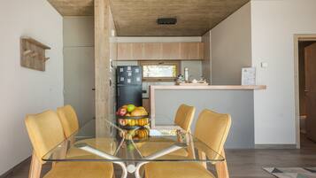 A modern kitchen with wooden cabinets, a glass dining table, and a fruit bowl.