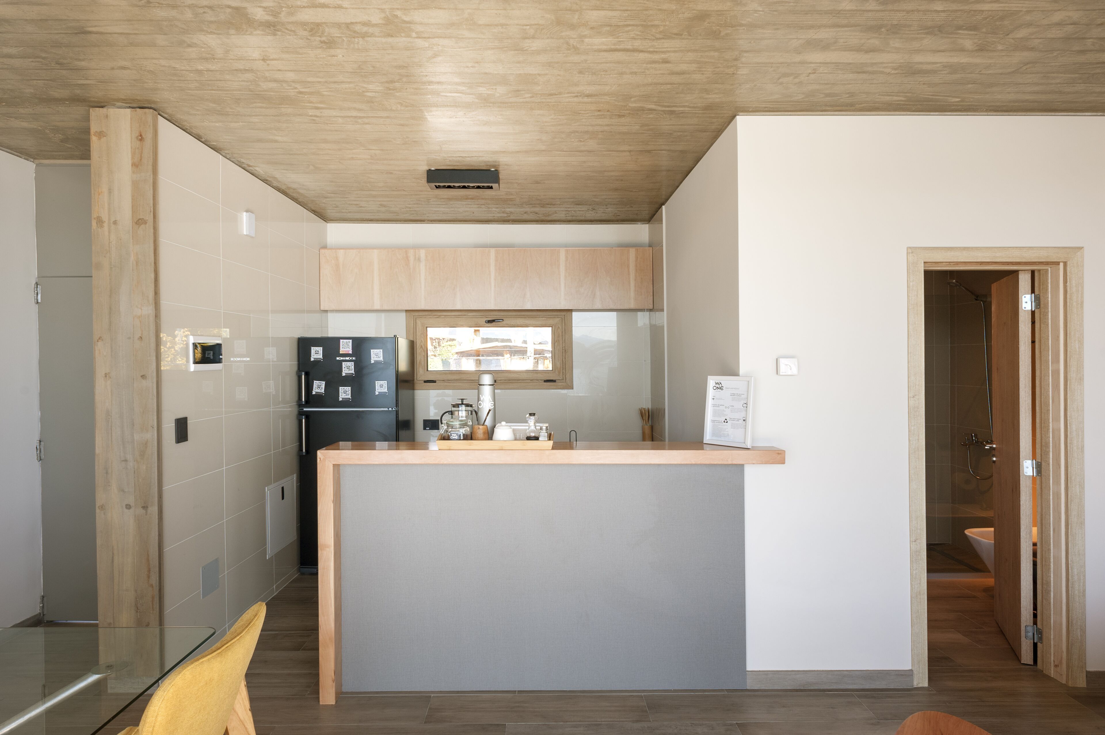 Une cuisine moderne dotée d’un îlot central, de meubles en bois et d’un four à micro-ondes encastré.