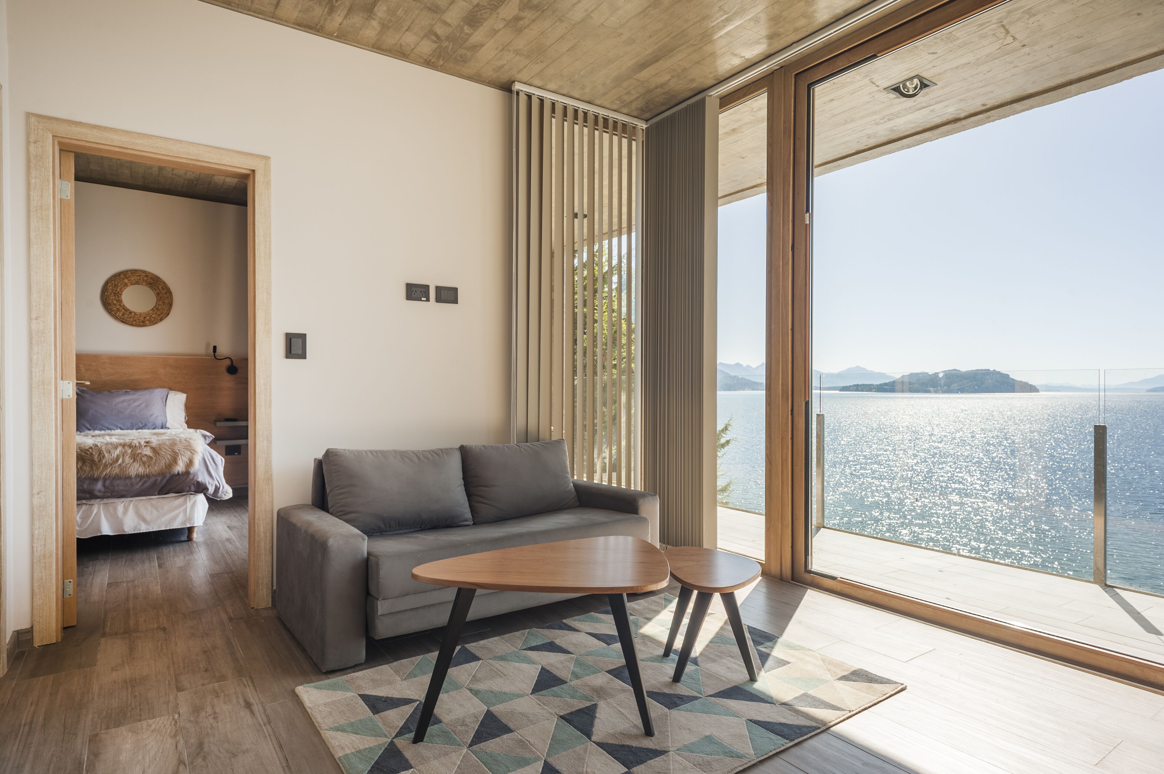 A modern room with a sofa, a small table, and a view of a body of water.