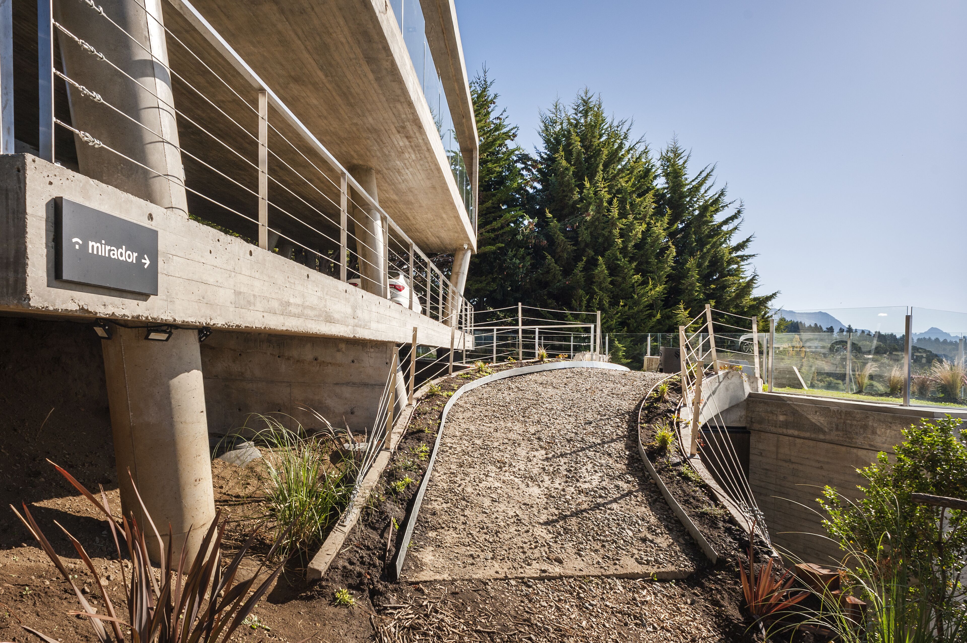 A concrete pathway leading to a building with a sign indicating 'mirador'.