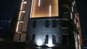 Un bâtiment moderne doté d’une façade originale, caractérisée par des lamelles de bois verticales et des bords illuminés.
