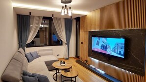 Un salon moderne avec un canapé, une table basse et un téléviseur fixé à un mur en bois.