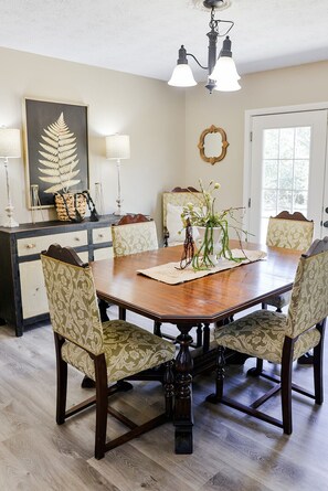 A dining room with a wooden table, patterned chairs, a decorative centerpiece, and a pendant light above.