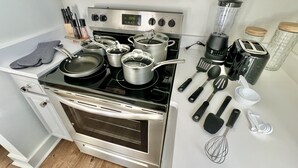 Cozinha equipada com eletrodomésticos de aço inoxidável, incluindo fogão, forno e liquidificador, além de diversos utensílios e recipientes de cozinha.