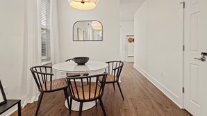 Uma sala de jantar com uma mesa redonda, quatro cadeiras e um lustre.