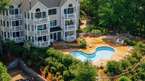 A multi-story building with a swimming pool, outdoor seating, and a deck. - Stony Brook 23 | Top Floor, Heated Pool, Lake Michigan View (Glen Arbor)