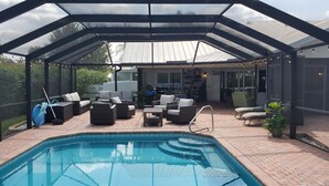 Un espace piscine extérieur abrité, doté de sièges et offrant une vue sur le jardin arrière.