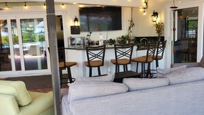 Une cuisine moderne dotée d’un bar, de grandes fenêtres et d’un coin salon avec un canapé et des fauteuils.