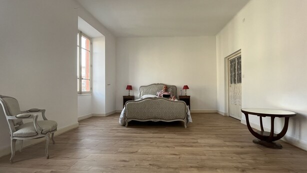 Een slaapkamer met een bed, twee nachtkastjes, een stoel en een ronde tafel.