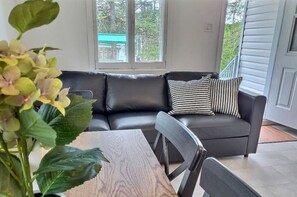 Relax in this stylish living room with a sofa, dining table, and potted plant, offering a view of the outdoors.