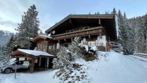 Un chalet en bois doté d’un porche et d’une voiture garée devant.