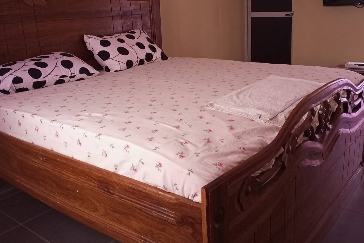 Een houten bed met een bloemenbedekking en twee polkadot kussens.
