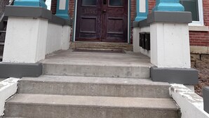 A front entrance with a dark wooden door, white and blue trim, and a brick building in the background. - Downtown Dubuque Retreat, Spa Access, Private Deck, One block to Farmers Market, (Dubuque)