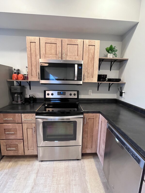 A kitchen with wooden cabinets, a microwave, a stove, and a dishwasher. - Downtown Dubuque Retreat, Spa Access, Private Deck, One block to Farmers Market, (Dubuque)