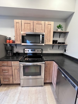 A kitchen with wooden cabinets, a microwave, a stove, and a dishwasher.