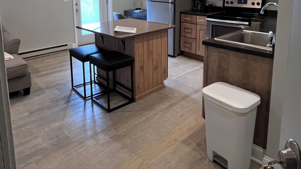A modern kitchen with a central island, wooden cabinets, stainless steel appliances, and a pendant light.