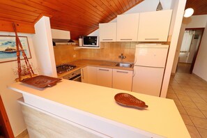 Cocina con alacenas blancas, microondas, estufa y pileta.