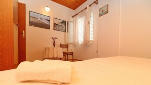 Una camera da letto con un letto, una sedia, un tavolo e una finestra con tende.