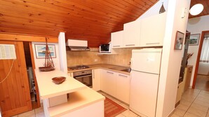 Una cucina compatta con mobili bianchi, un forno a microonde, un piano cottura e un frigorifero.