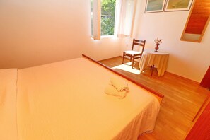 Un dormitorio con una cama, una silla, una mesita y una ventana.