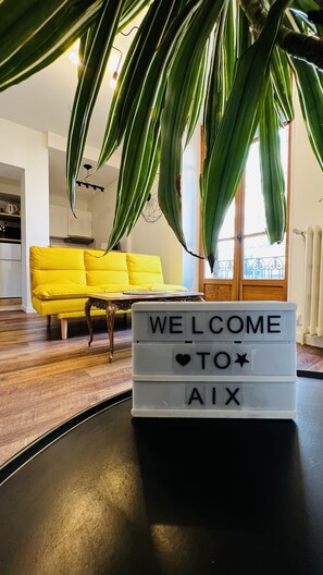 A modern living room with a yellow sofa, a coffee table, and a welcome sign.