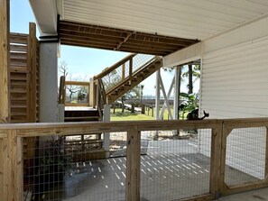 outdoor space with a staircase leading to an upper level, enclosed by a fence and wire mesh barrier.