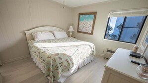 Un dormitorio con cama, escritorio, lámpara y ventana con vistas.