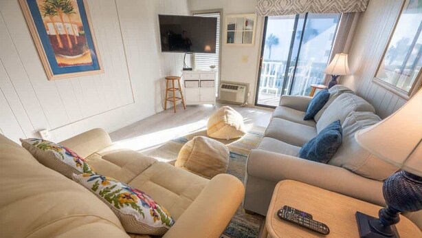 Una sala de estar con sofá, mesa de centro, televisor y un balcón con vistas.