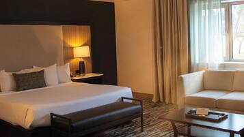 Une chambre d’hôtel avec un grand lit, une table de chevet avec une lampe, un canapé et une table basse.
