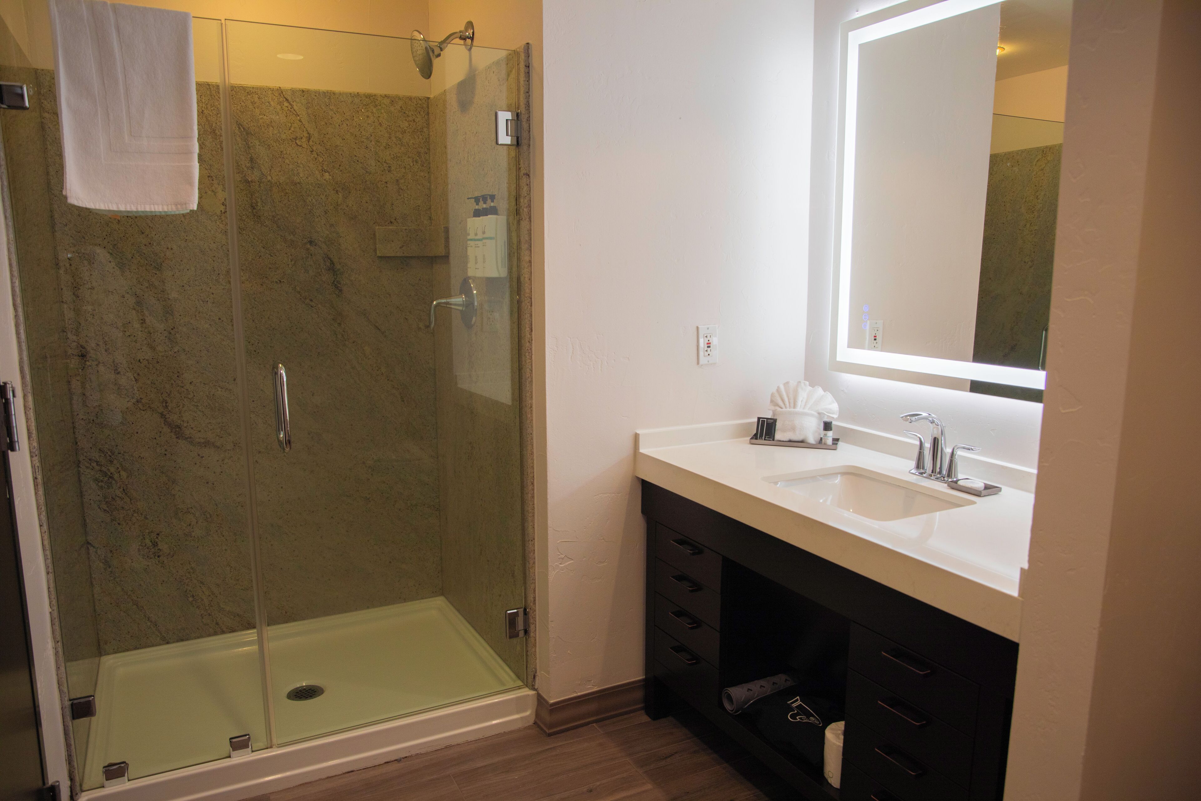 Une salle de bain moderne avec une douche à parois de verre, un lavabo blanc et un grand miroir.